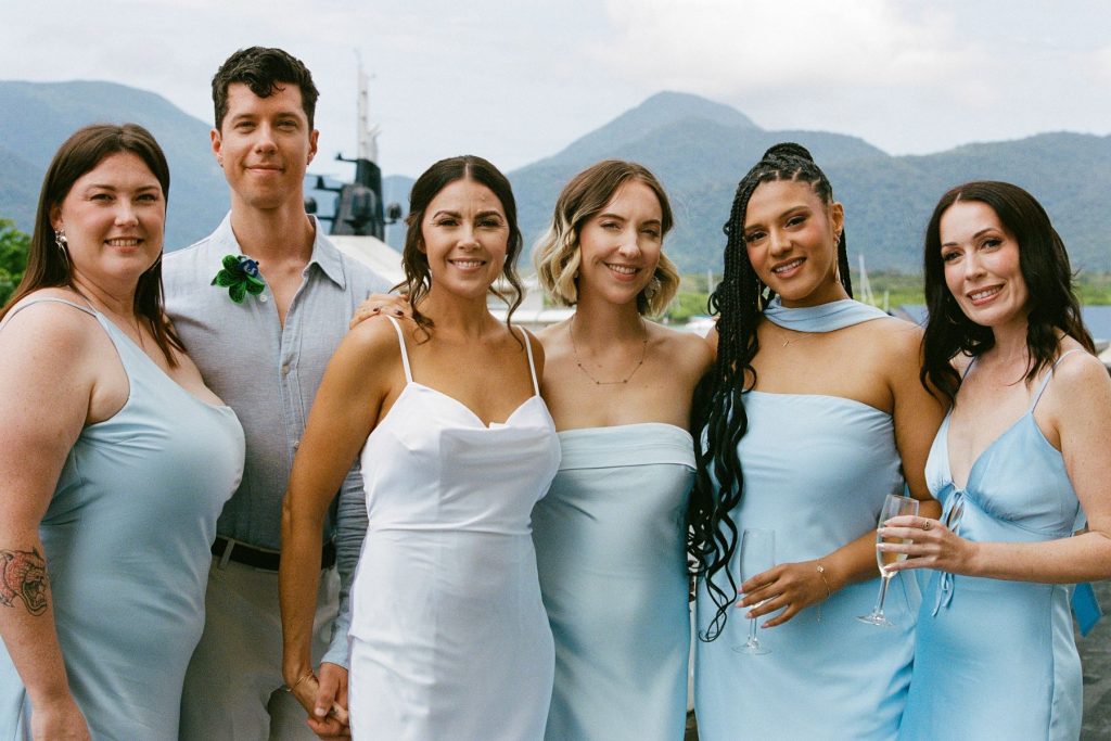 A vibrant color film photograph of a bride and her bridesmaids sharing a joyful moment together; featuring soft, natural light and timeless film tones by Phoebe Kate Photography.