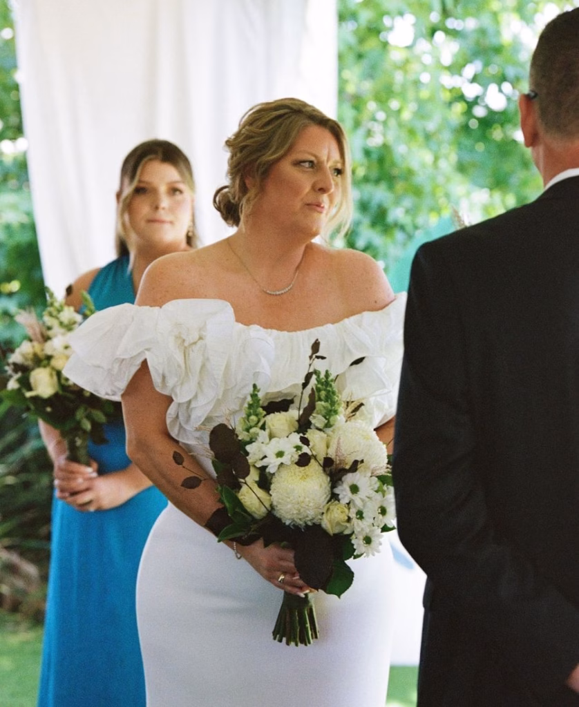 A black and white 35mm film photograph capturing an emotional moment as a bride says her wedding vows; featuring raw sentiment and authentic film grain by Phoebe Kate Photography.
