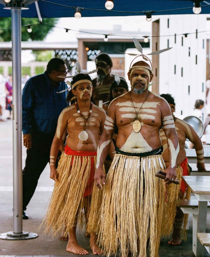 A vibrant color film shot of Torres Strait Islander cultural dancers performing at a wedding reception, showcasing traditional dress and heritage.